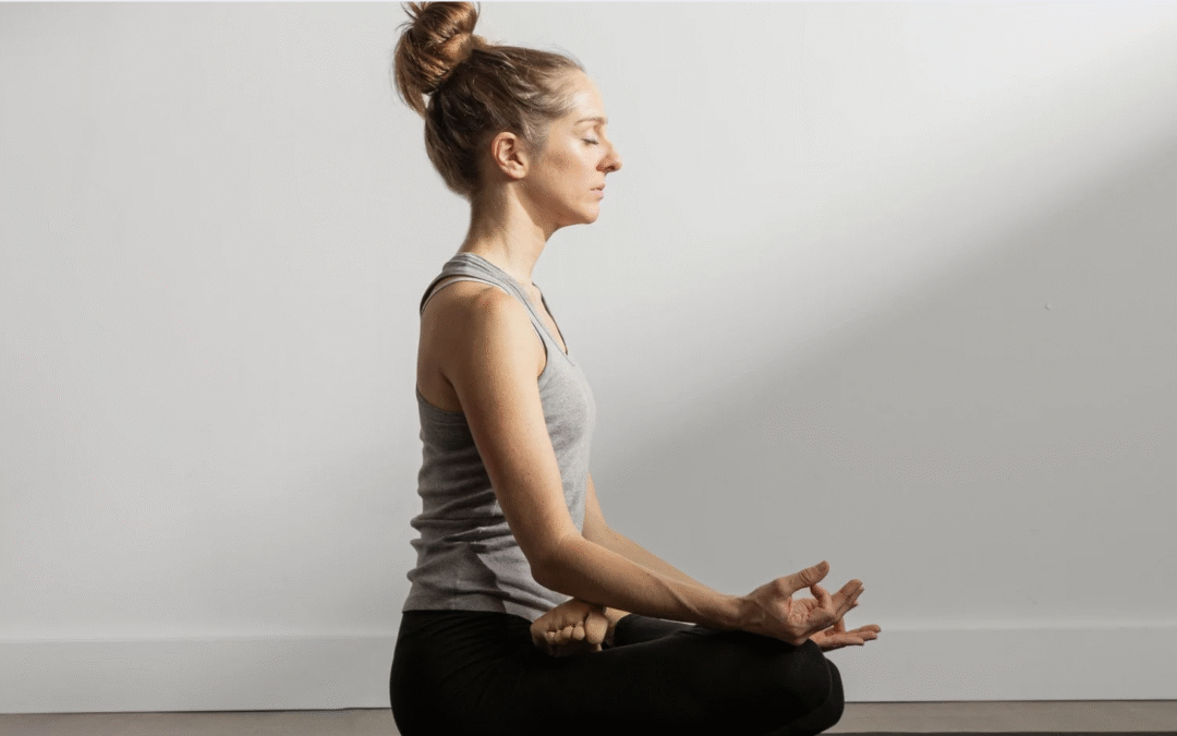 Kvinna sitter i meditationsställning med rak rygg och händerna i gyan mudra